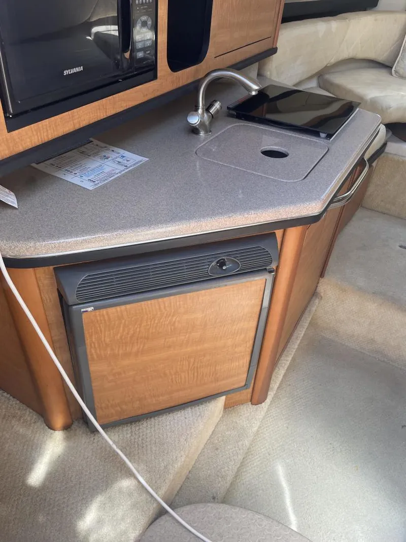 Slide: The Image of 2006 Sea Ray 270 Amberjack interior kitchenette with sink, microwave, and mini-fridge. - 5