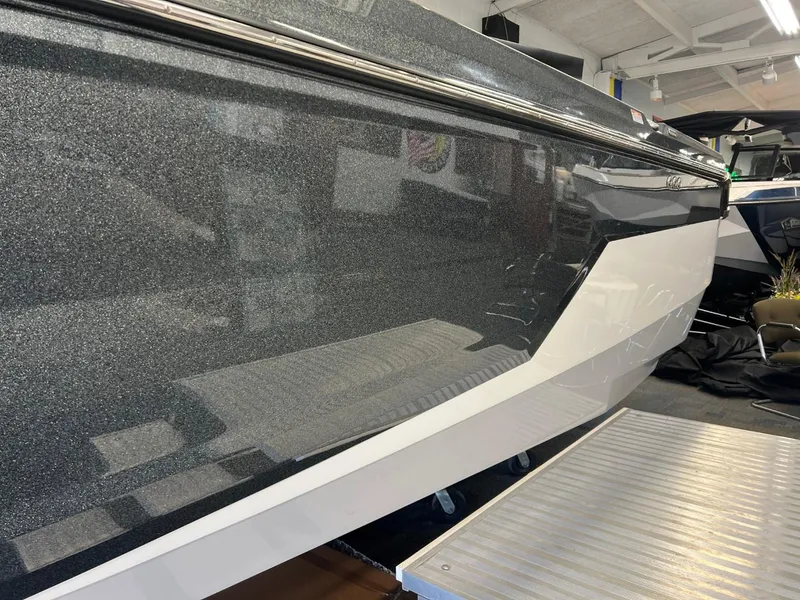 Slide: The Image of 2024 Nautique Super Air Nautique GS24 boat side view in showroom. - 11