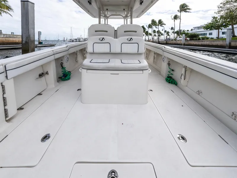 Slide: The Image of 2017 Jupiter 34 HFS boat interior with seating and storage, docked near palm trees. - 19