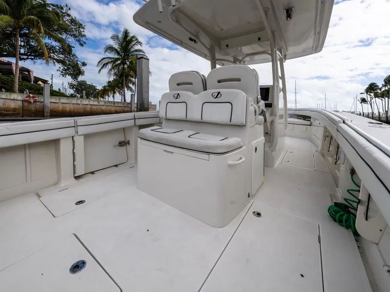 Slide: The Image of 2017 Jupiter 34 HFS boat interior with seating and helm, docked near palm trees. - 20