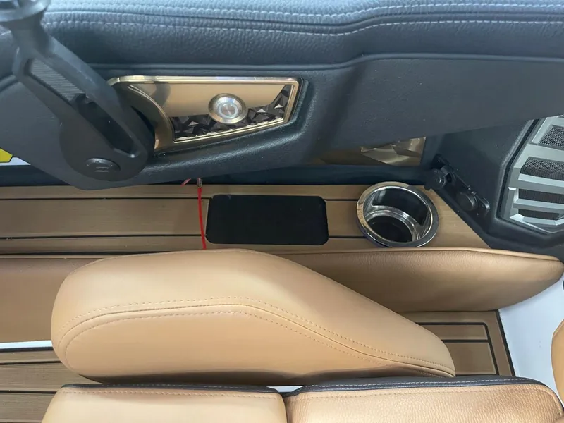 Slide: The Image of 2024 Nautique Super Air Nautique G23 interior with tan leather seats and cup holder. - 13