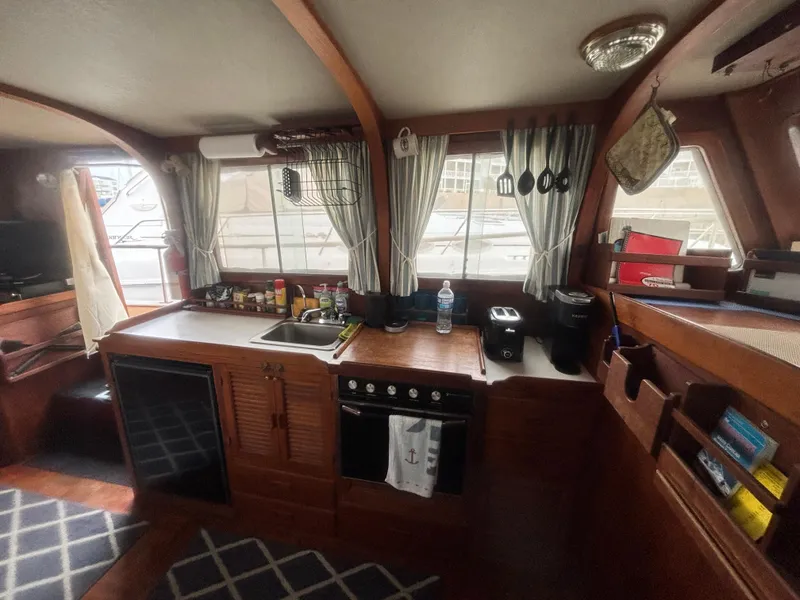 Slide: The Image of 1983 Albin Double Cabin kitchen with wooden cabinetry, stove, and windows. Cozy nautical interior. - 24