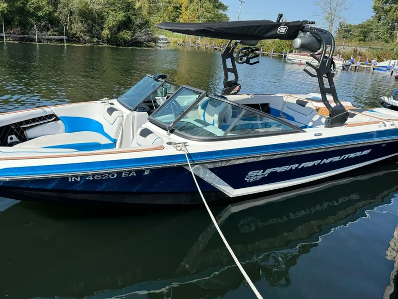 Slide: The Image of 2018 Nautique Super Air Nautique GS24 boat docked on a calm lake. - 15
