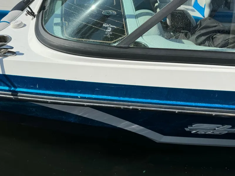 Slide: The Image of 2018 Nautique Super Air Nautique GS24 boat side view with blue and white detailing. - 18
