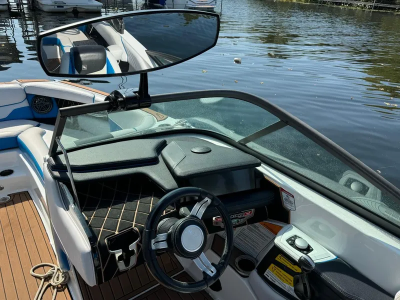 Slide: The Image of 2018 Nautique Super Air Nautique GS24 boat interior with steering wheel and dashboard, docked on water. - 23