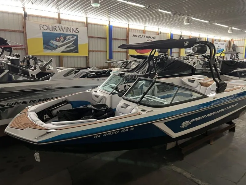 Slide: The Image of 2018 Nautique Super Air Nautique GS24 boat in showroom, blue and white exterior. - 3