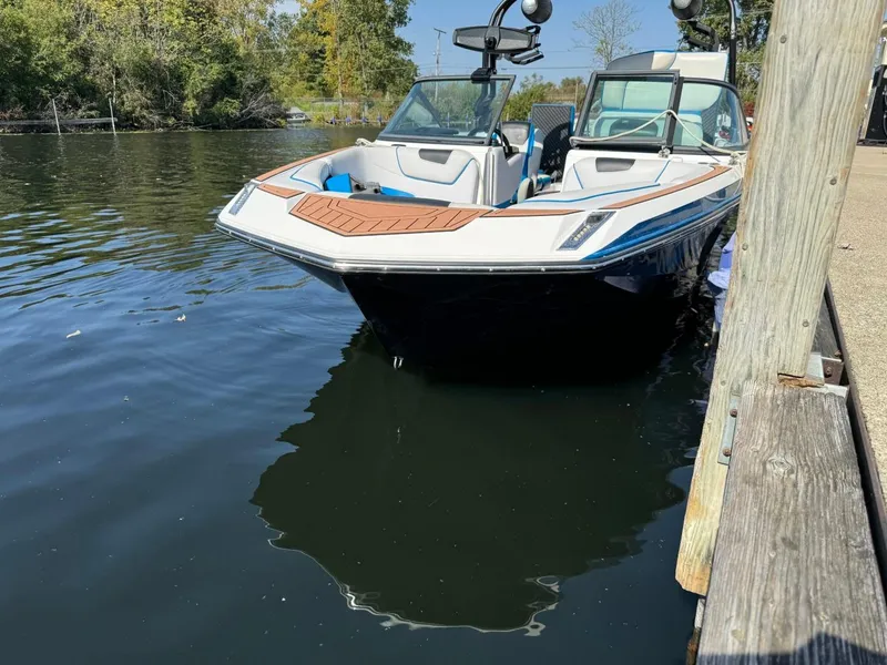Slide: The Image of 2018 Nautique Super Air Nautique GS24 boat docked on calm water. - 46