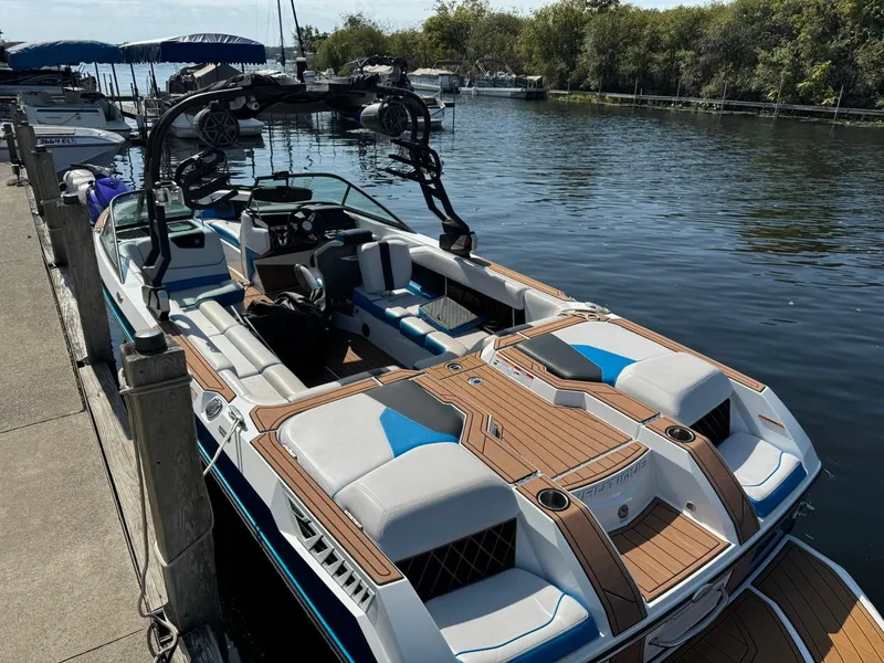 Slide: The Image of 2018 Nautique Super Air Nautique GS24 boat docked by a serene lake. - 6