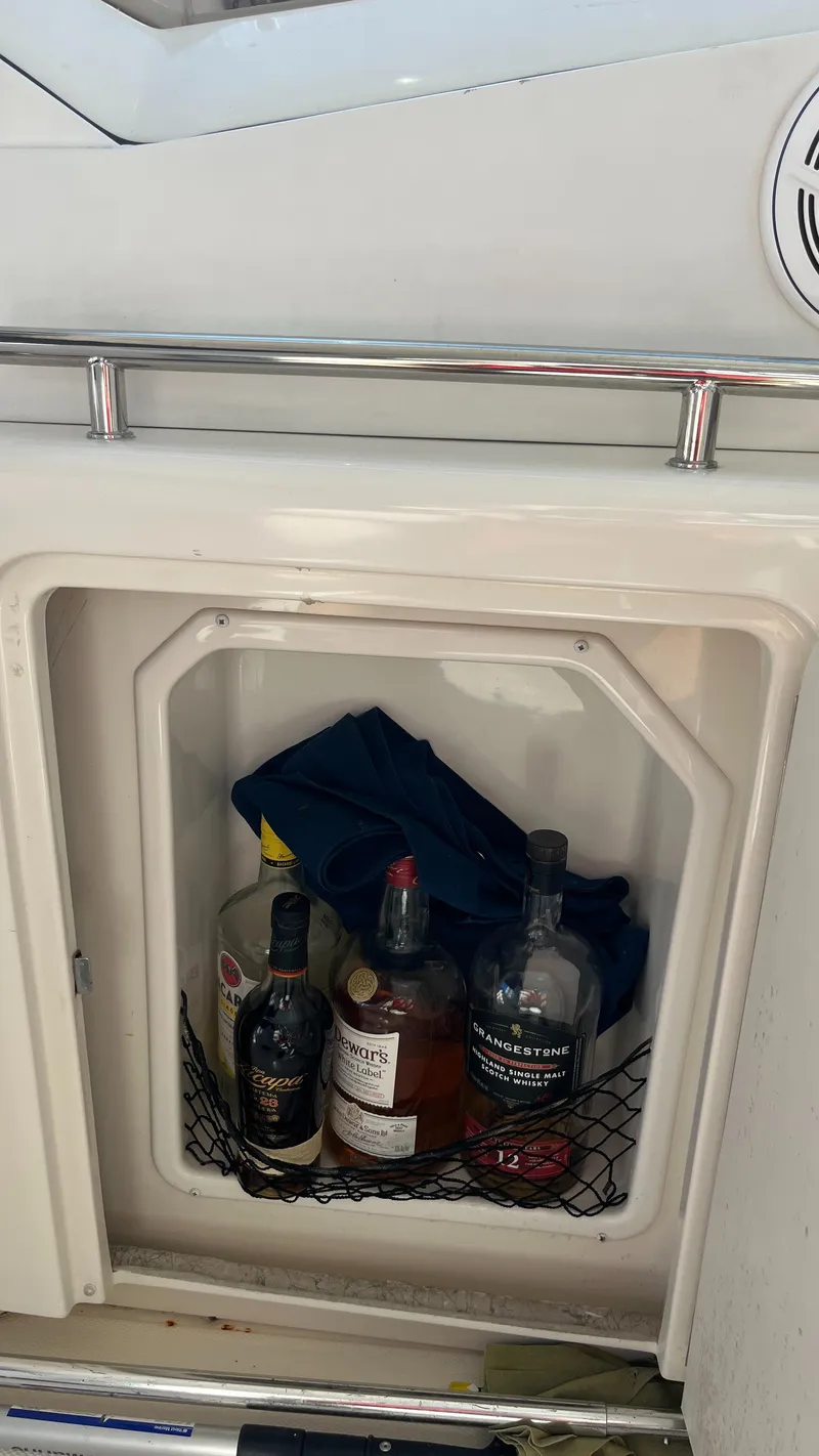 Slide: The Image of Cabinet on 2008 Sea Ray 380 Sundancer with assorted liquor bottles and a blue cloth. - 20