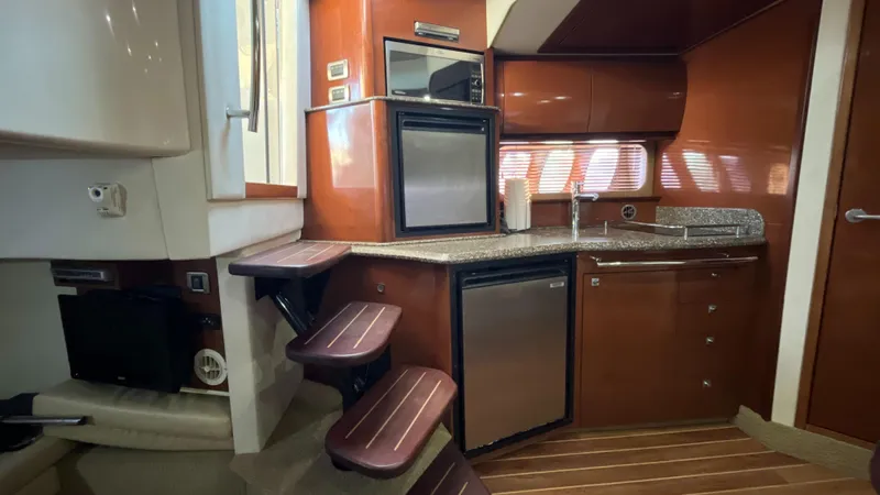 Slide: The Image of 2008 Sea Ray 380 Sundancer interior with kitchenette, featuring wood cabinetry and modern appliances. - 38