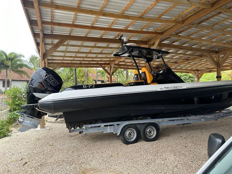 Slide: The Image of 2019 Technohull SeaDNA 999 G5 boat on trailer under a wooden shelter. - 0