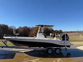 Slide: The Image of 2019 NauticStar 244XTS boat on trailer, parked outdoors under clear blue sky. - 2