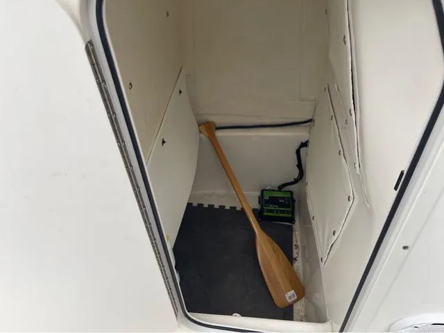 Slide: The Image of 2019 NauticStar 244XTS storage compartment with paddle and battery. - 32