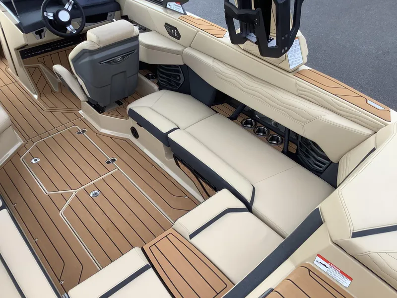 Slide: The Image of 2025 Nautique G23 boat interior with tan upholstery and wood-style flooring. - 11