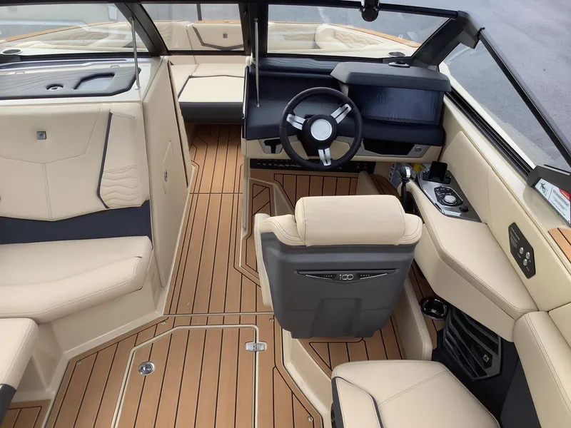 Slide: The Image of 2025 Nautique G23 boat interior with beige seating and modern dashboard. - 13
