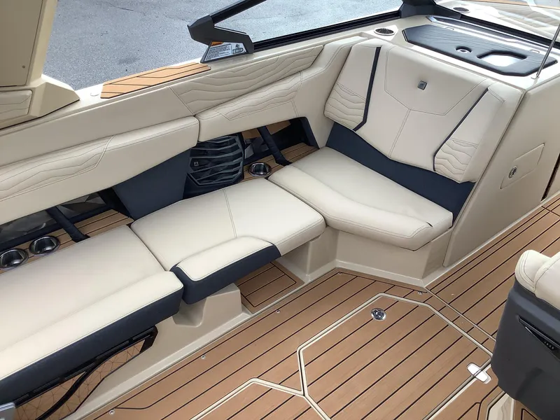 Slide: The Image of 2025 Nautique G23 boat interior with beige seating and teak flooring. - 14