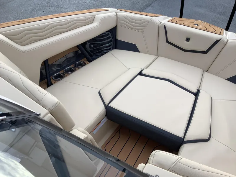 Slide: The Image of 2025 Nautique G23 boat interior with beige seating and cup holders. - 16