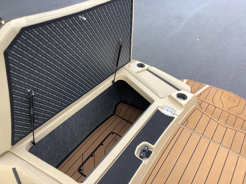 Slide: The Image of 2025 Nautique G23 boat storage compartment with open hatch and cup holders. - 19