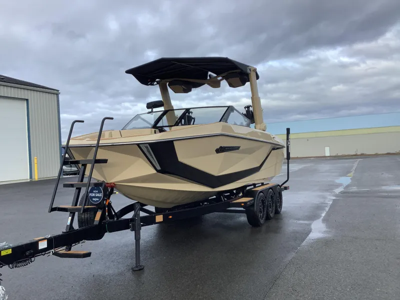 Slide: The Image of 2025 Nautique G23 boat on trailer, parked outdoors, overcast sky. - 2