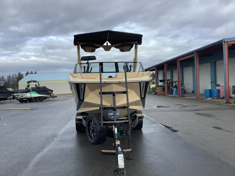Slide: The Image of 2025 Nautique G23 boat on trailer in industrial area, overcast sky. - 3