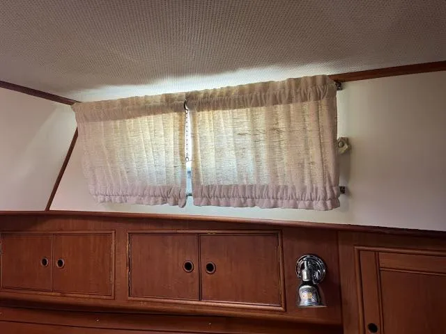 Slide: The Image of Interior of 1999 Grand Banks Eastbay 38 with wooden cabinets and curtained window. - 27