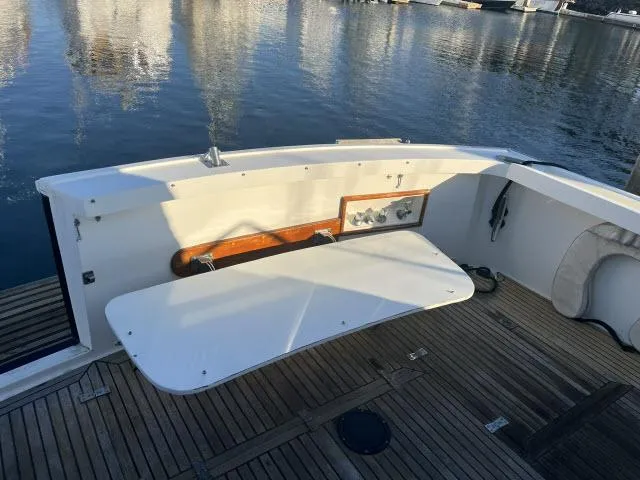 Slide: The Image of 1999 Grand Banks Eastbay 38 boat deck with foldable table and wooden flooring. - 34