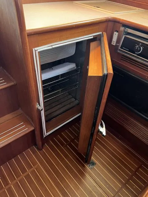 Slide: The Image of 1999 Grand Banks Eastbay 38 yacht interior with open wooden cabinet and refrigerator. - 7