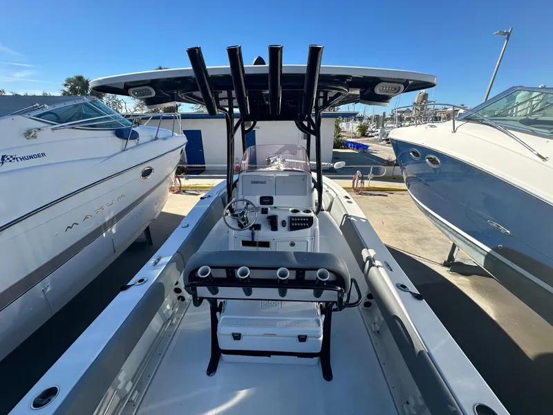 Slide: The Image of 2022 NauticStar Legacy 2302 boat interior with console and seating, docked between two other boats. - 25