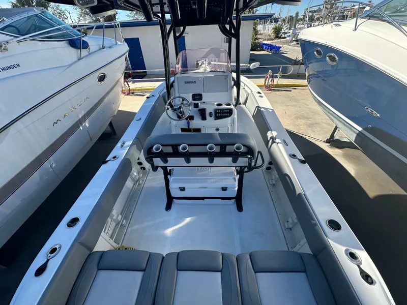 Slide: The Image of 2022 NauticStar Legacy 2302 boat interior with seating and console, docked between two other boats. - 26