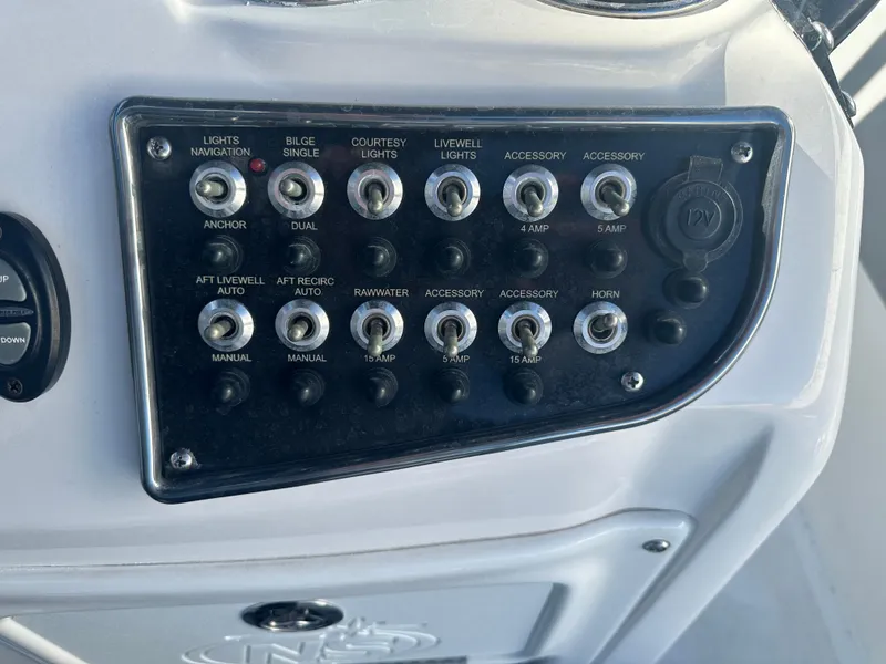 Slide: The Image of Control panel of 2022 NauticStar Legacy 2302 boat with various switches and dials. - 33