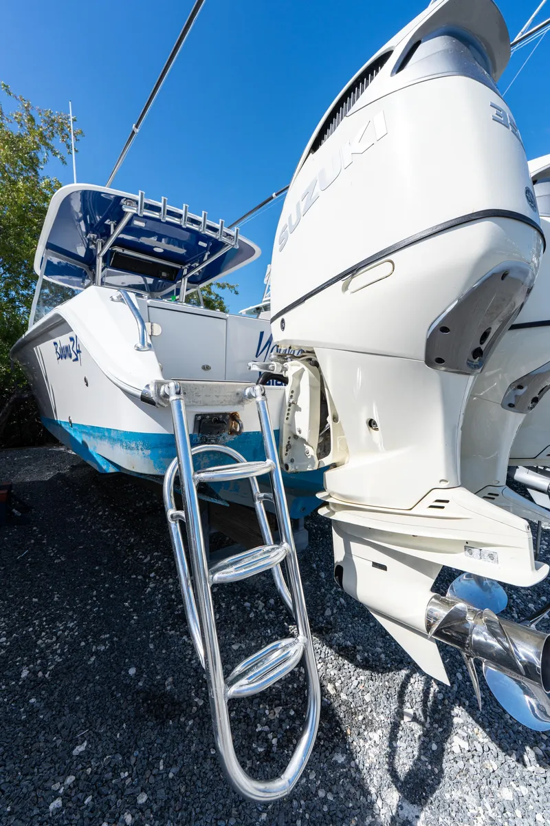 Slide: The Image of 2015 Bahama 34 boat with dual outboard engines and ladder, parked on gravel. - 38