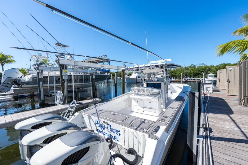 Slide: The Image of 2015 Bahama 34 boat docked with triple outboard engines, clear blue sky, and marina view. - 41