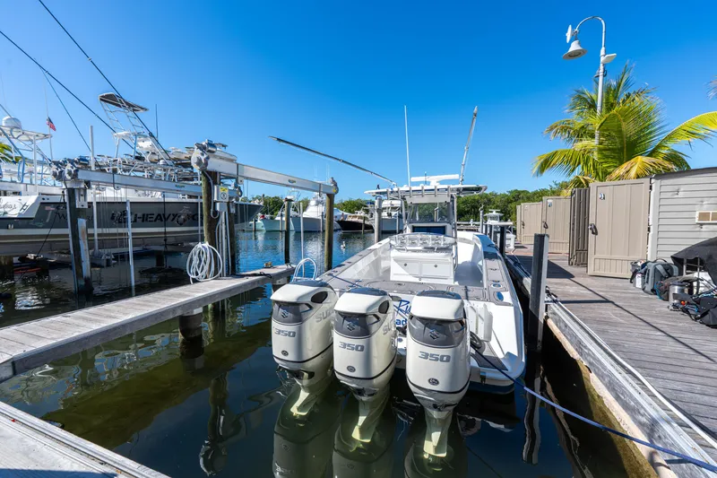 Slide: The Image of 2015 Bahama 34 boat docked with triple 350 engines, clear blue sky, and palm tree. - 42