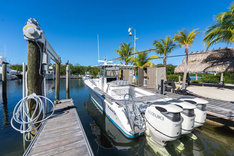 Slide: The Image of 2015 Bahama 34 boat docked with Suzuki engines, surrounded by palm trees and clear blue sky. - 43