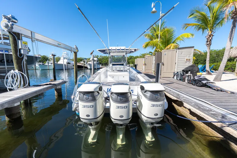 Slide: The Image of 2015 Bahama 34 boat with triple 350 engines docked by palm trees. - 45