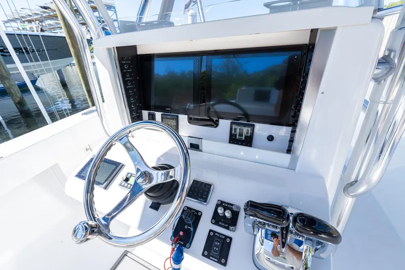 Slide: The Image of 2015 Bahama 34 boat helm with steering wheel, dual screens, and control panel. - 48