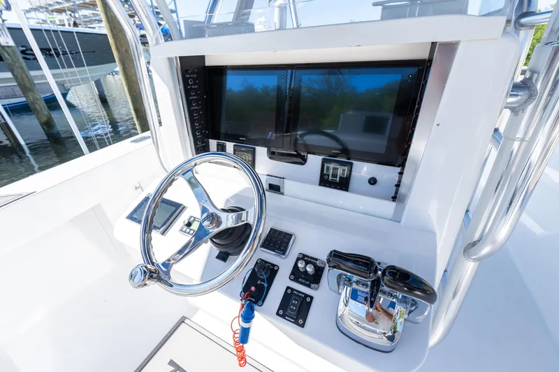 Slide: The Image of Control panel of a 2015 Bahama 34 boat with steering wheel and navigation screens. - 49