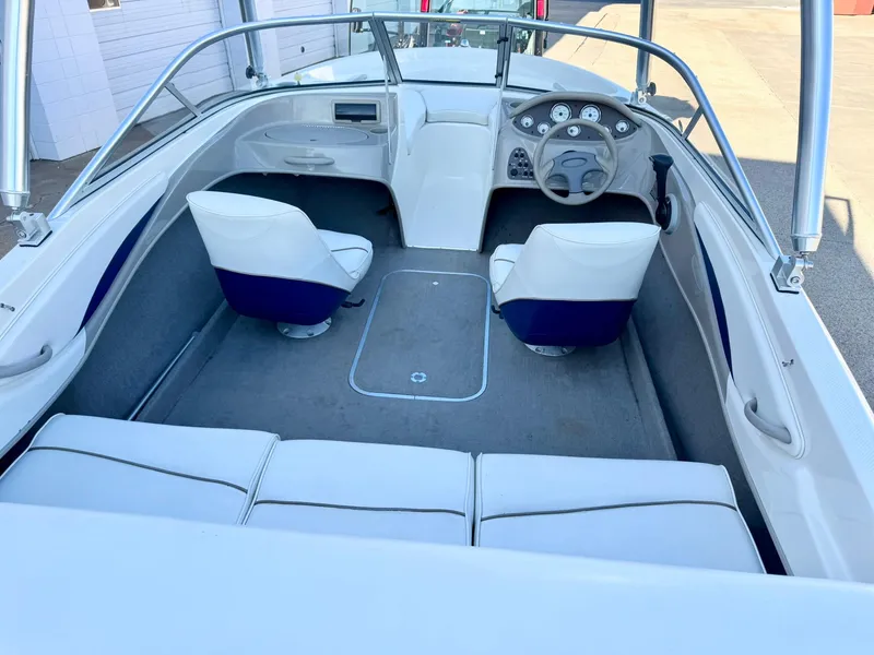 Slide: The Image of 2002 Bayliner 185 BR boat interior with white seating and dashboard. - 14