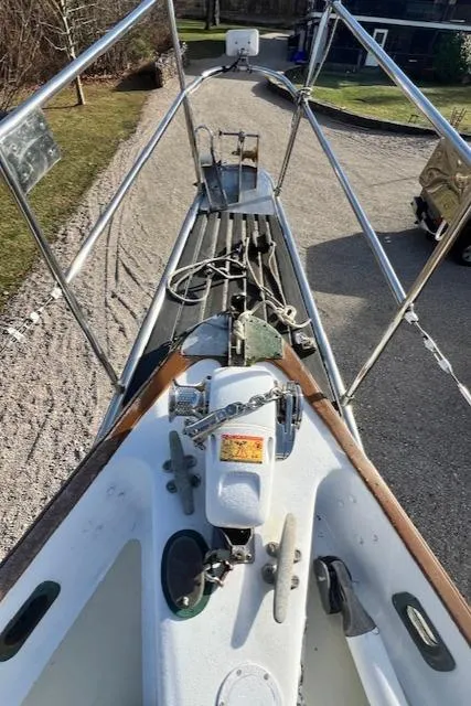 Slide: The Image of 1980 Kaiser Gale Force 34 sailboat deck with anchor and railing, docked on gravel. - 13