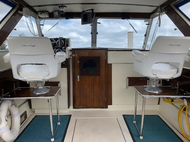 Slide: The Image of 1968 Chris-Craft 31 Commander boat interior with white captain chairs and wooden dashboard. - 11