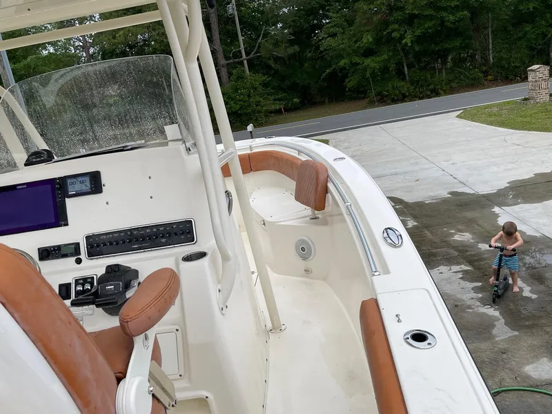 Slide: The Image of 2017 Cobia 261 Center Console boat with tan seats, parked near a child on a tricycle. - 27