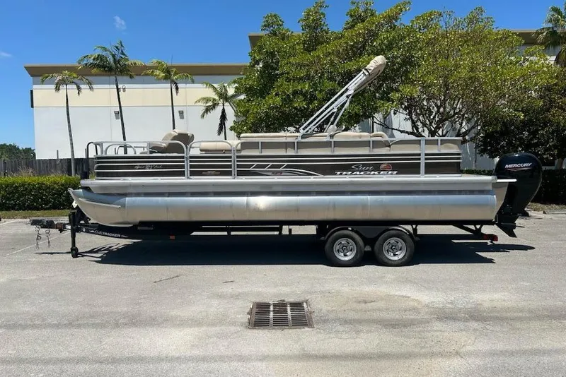 The Image of 2025 Sun Tracker Sportfish 24 XP3 pontoon boat on trailer, parked outdoors. - 0