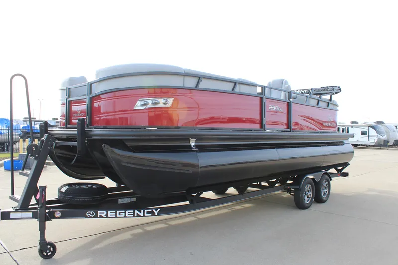 Slide: The Image of 2025 Regency 230 DL3 pontoon boat, red exterior, parked outdoors under a blue sky. - 3