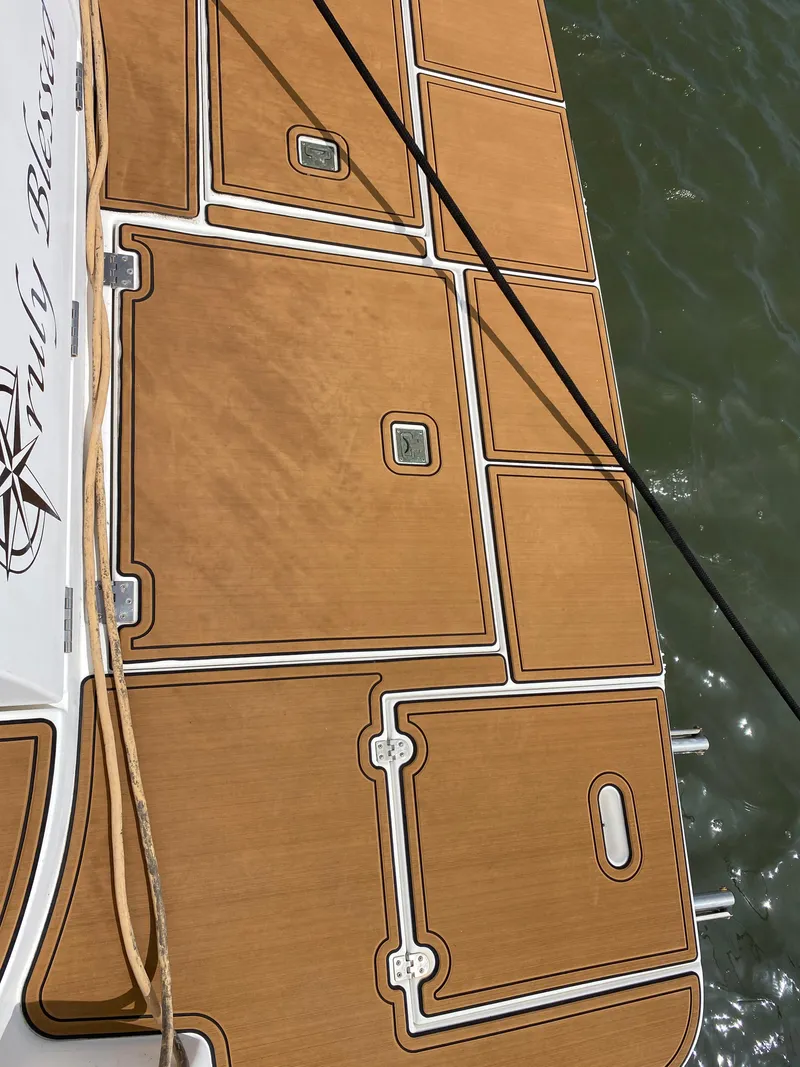 Slide: The Image of Cruisers 3672 2000 model boat deck with teak flooring, docked on water. - 2