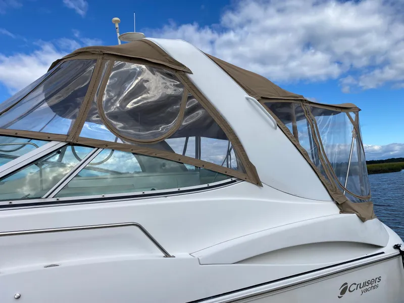 Slide: The Image of 2000 Cruisers 3672 yacht with tan canopy, docked under a blue sky. - 3