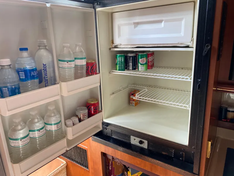 Slide: The Image of Open refrigerator in 2000 Cruisers 3672 yacht, stocked with drinks and water bottles. - 17