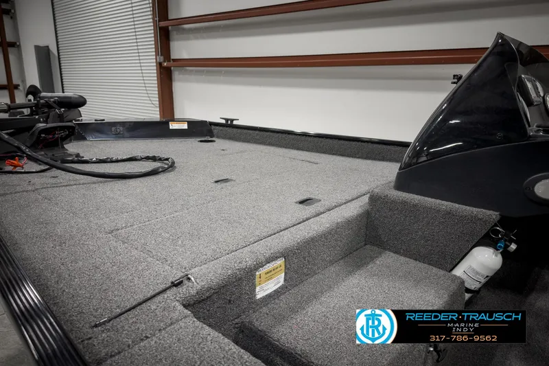 Slide: The Image of 2021 Lowe Skorpion 17 boat interior with carpeted deck in a garage setting. - 11