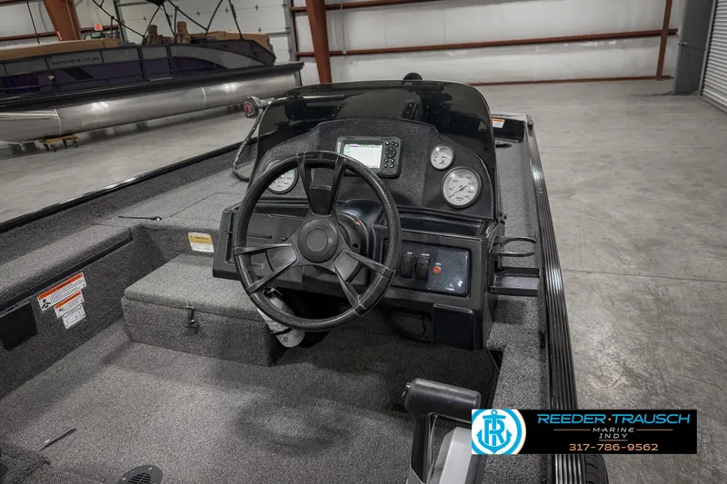 Slide: The Image of 2021 Lowe Skorpion 17 boat dashboard with steering wheel and gauges in a warehouse. - 23