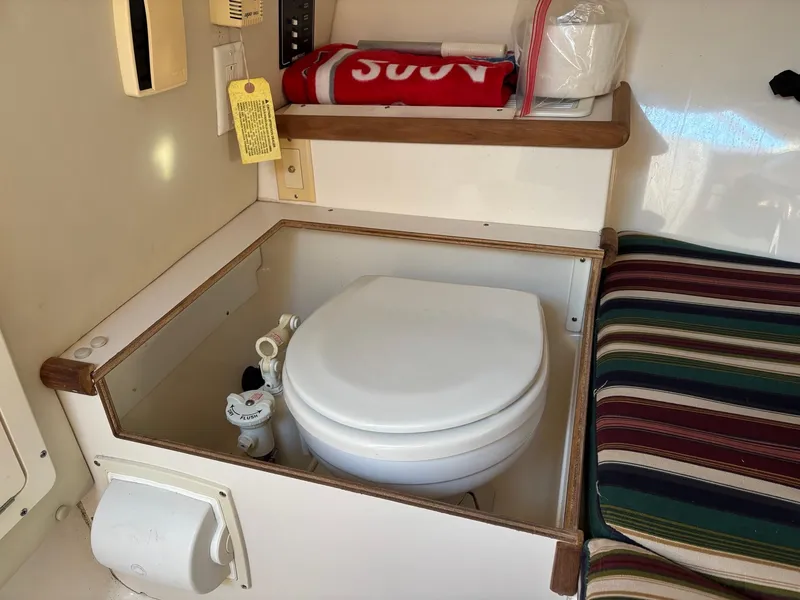 Slide: The Image of Compact marine toilet in 2003 Pursuit 2670 Denali LS cabin, with striped cushion nearby. - 22
