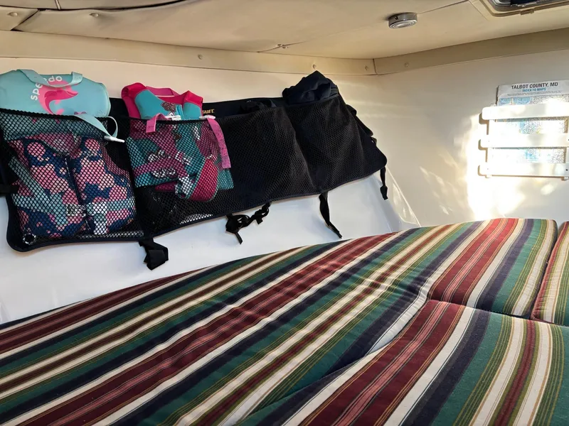 Slide: The Image of Interior cabin of 2003 Pursuit 2670 Denali LS with striped bedding and storage nets. - 26